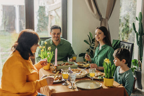 Glückliche Familie genießt die Mahlzeit auf dem Esstisch beim Osteressen - VSNF01664