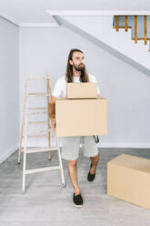 Man carrying cardboard boxes at new home - DAMF01305