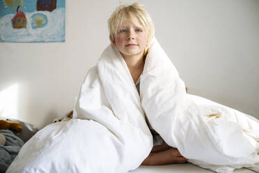 Lazy boy wrapped in blanket and sitting on bed at home - NJAF00770