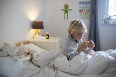 Little girl in underwear sitting on bed looking at smartphone