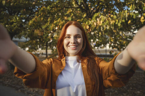 Lächelnde Frau nimmt Selfie in der Nähe von Baum im Herbst - ALKF00970