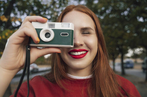 Lächelnde Frau, die ein Bild durch eine Kamera im Herbstpark macht - ALKF00976
