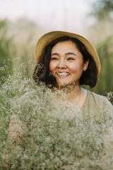 Happy woman with bunch of gypsophila flowers in field - IEF00578