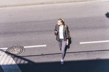 Geschäftsfrau beim Überqueren der Straße an einem sonnigen Tag - UUF31272