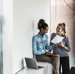 Happy business colleagues having discussion over documents in office - UUF31278