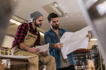 Junge Schreiner lesen in der Werkstatt den Bauplan - UUF31299