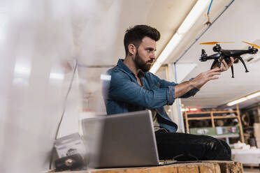 Junger, zielstrebiger Ingenieur bei der Untersuchung einer Drohne im Workshop - UUF31305