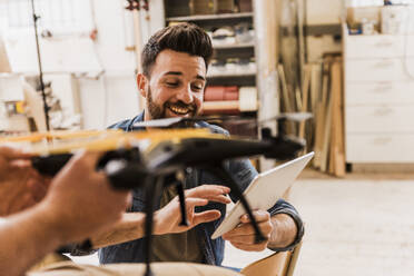 Happy engineer programming drone with tablet PC at workshop - UUF31307