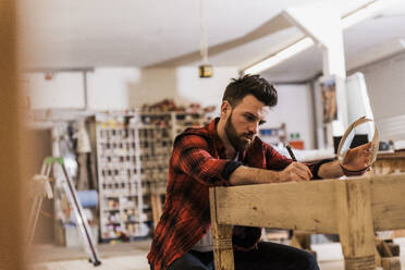 Tischler bei der Arbeit mit einem Holzgegenstand am Tisch in der Werkstatt - UUF31318