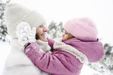 Happy mother spending leisure time with daughter in winter park - EYAF02956