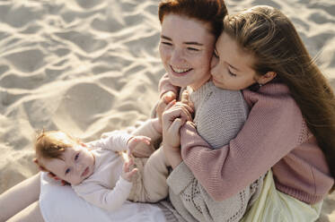 Happy woman sitting with daughters at beach - ALKF00998