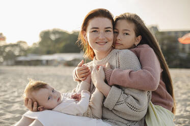 Happy woman spending leisure time with daughters at beach - ALKF00999