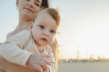 Cute baby girl with mother at sunset - ALKF01038