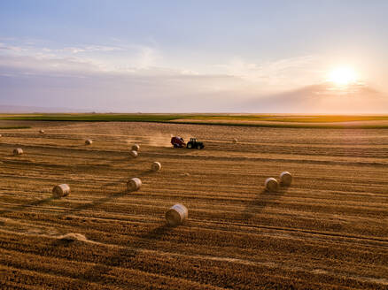 Tractor baling wheat field at sunset - NOF00926