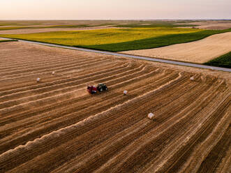 Tractor baling hay on harvested wheat field - NOF00929