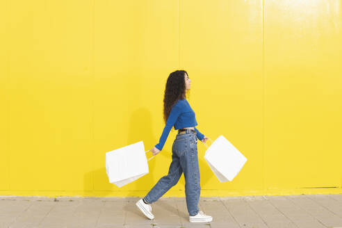 Frau mit Einkaufstaschen in der Nähe der gelben Wand - MGRF01087