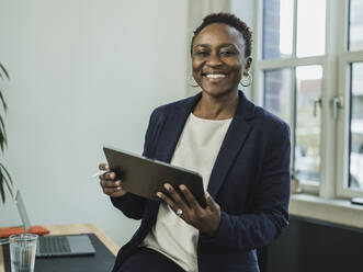Lächelnde Geschäftsfrau mit Tablet-PC im Büro - MFF09550