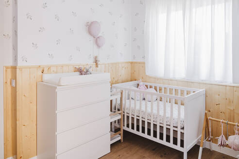 Decorated nursery room with crib and dresser near window - EBBF08665