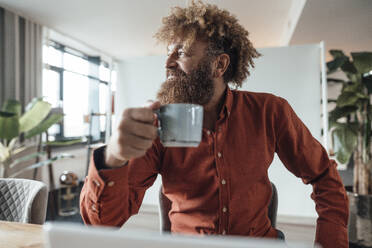 Mature businessman with afro hairstyle holding coffee cup in office cafeteria - JOSEF23433