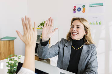 Happy businesswoman giving high-five to colleague at office - XLGF03363