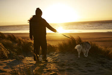 Young woman walking dog at beach - ANNF00839