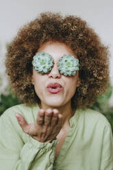 Frau trägt Echeveria-Blüten-Brille und bläst Kuss - YTF01820