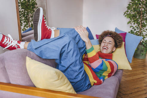 Lächelnde junge Frau auf dem Sofa zu Hause liegend - YTF01840