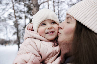Junge Mutter küsst Tochter im Winterpark - MBLF00261