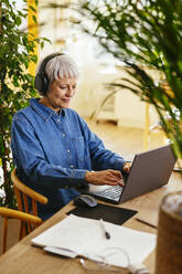 Smiling freelancer typing on laptop at home office - EBSF04393