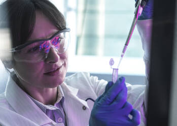 Wissenschaftlerin beim Pipettieren von Zellproben in ein Reagenzglas im Labor - ABRF01149