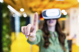 Geschäftsfrau trägt Virtual-Reality-Simulator und gestikuliert im Büro - WPEF08425