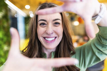 Happy businesswoman making finger frame in office - WPEF08427