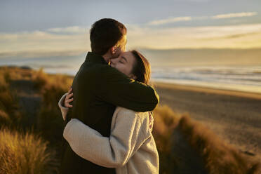 Junger Mann umarmt Freundin am Strand - ANNF00851