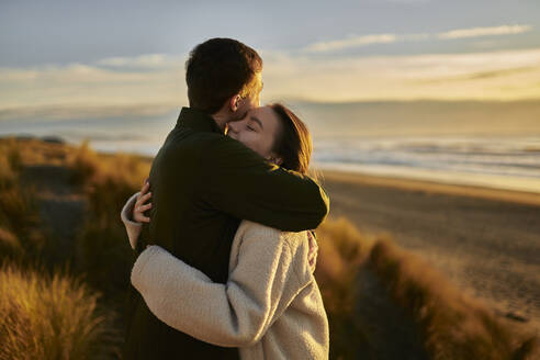 Young man embracing girlfriend at beach - ANNF00851