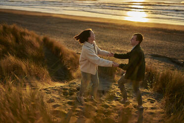 Playful couple enjoying vacations at ocean beach - ANNF00853