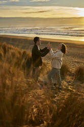 Girlfriend and boyfriend clasping hands at beach - ANNF00855