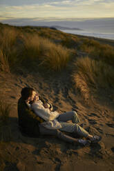 Junges Paar entspannt am Strand bei Sonnenuntergang - ANNF00867