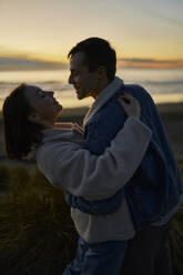 Smiling man and woman doing romantic dance at ocean beach - ANNF00934