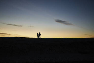 Junger Mann und Frau halten sich an einem ruhigen Strand am Meer - ANNF00938