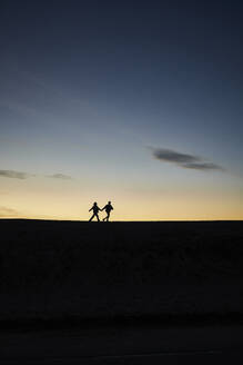 Silhouette of young couple running together at beach - ANNF00941