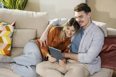 Loving young couple using tablet PC on sofa - UUF31339