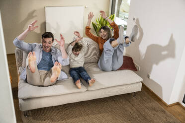 Cheerful family enjoying together on sofa at home - UUF31353