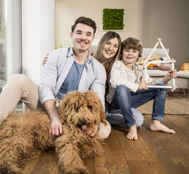 Happy family with model house and dog at home - UUF31363