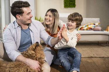 Happy mother with father and son giving high-five at home - UUF31366