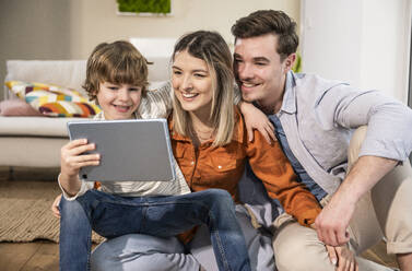 Happy family using tablet PC at home - UUF31369