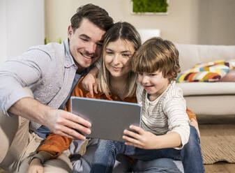 Lächelnde Familie bei der Nutzung eines Tablet-PCs zu Hause - UUF31370