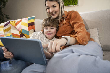 Happy boy with mother using tablet PC at home - UUF31377