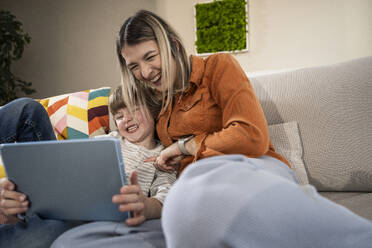 Fröhlicher Junge mit Mutter bei der Nutzung eines Tablet-PCs zu Hause - UUF31378
