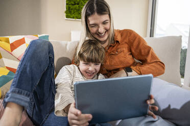 Cheerful mother and son using tablet PC at home - UUF31379