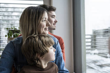 Familie schaut durch das Fenster zu Hause - UUF31403